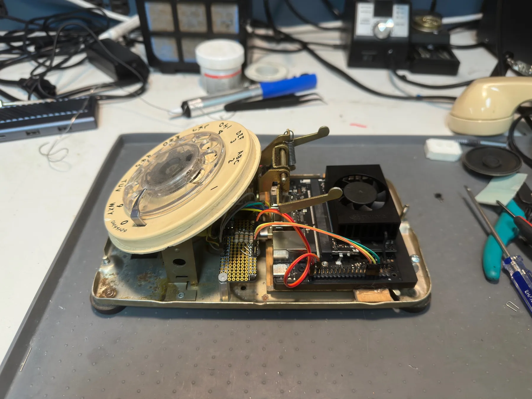 The telephone’s base plate with the rotary dial and a small computer board with a fan mounted beneath it