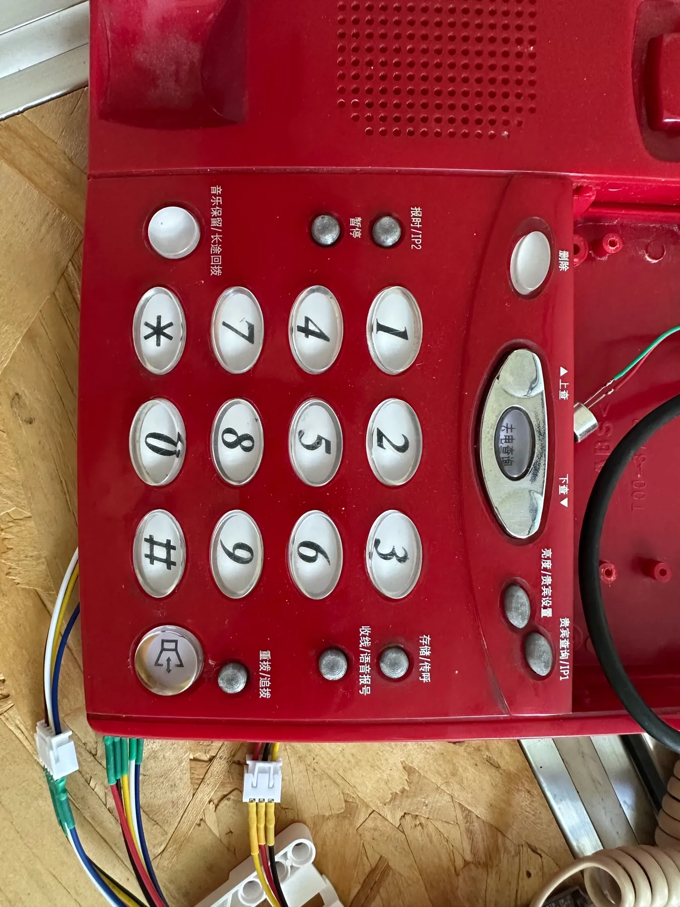 Close view of the red telephone’s clear plastic number keys, with new wiring beside it